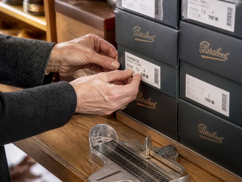 Plan rapproché des boîtes de chaussures et d’un outil de pointure sur le comptoir.