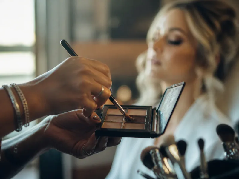 Geste précis du maquillage des yeux avec lumière naturelle et ambiance chaleureuse.
