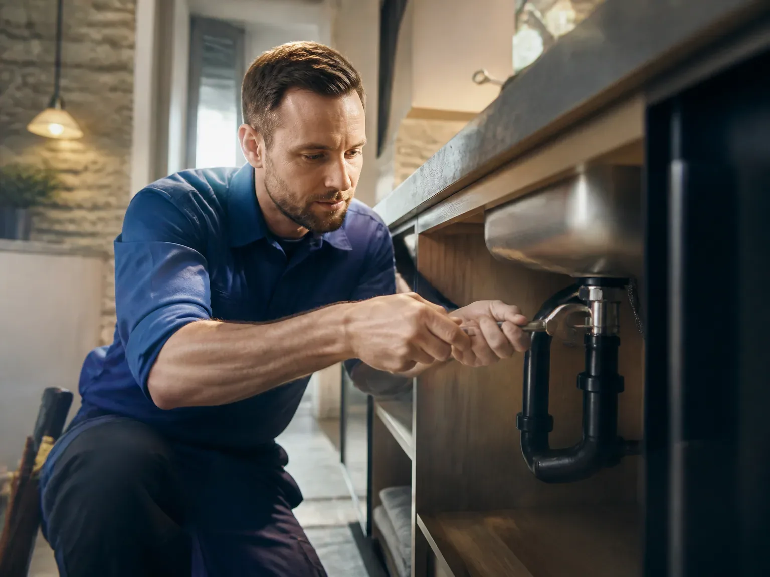 Plombier en action répare une canalisation dans une cuisine lumineuse